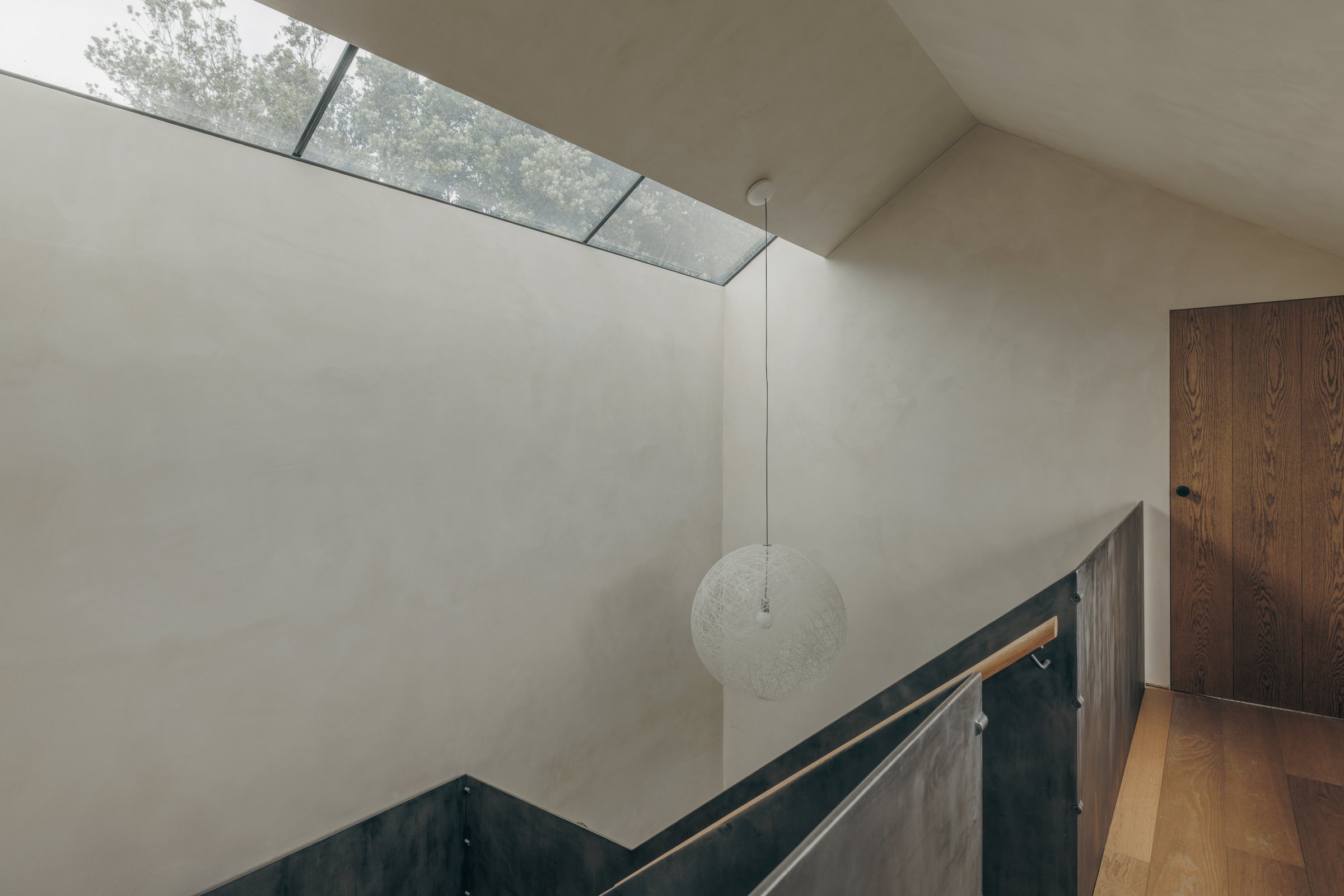 Rooflit staircase and landing with a timber handrail at Bank Cottage, Bryher