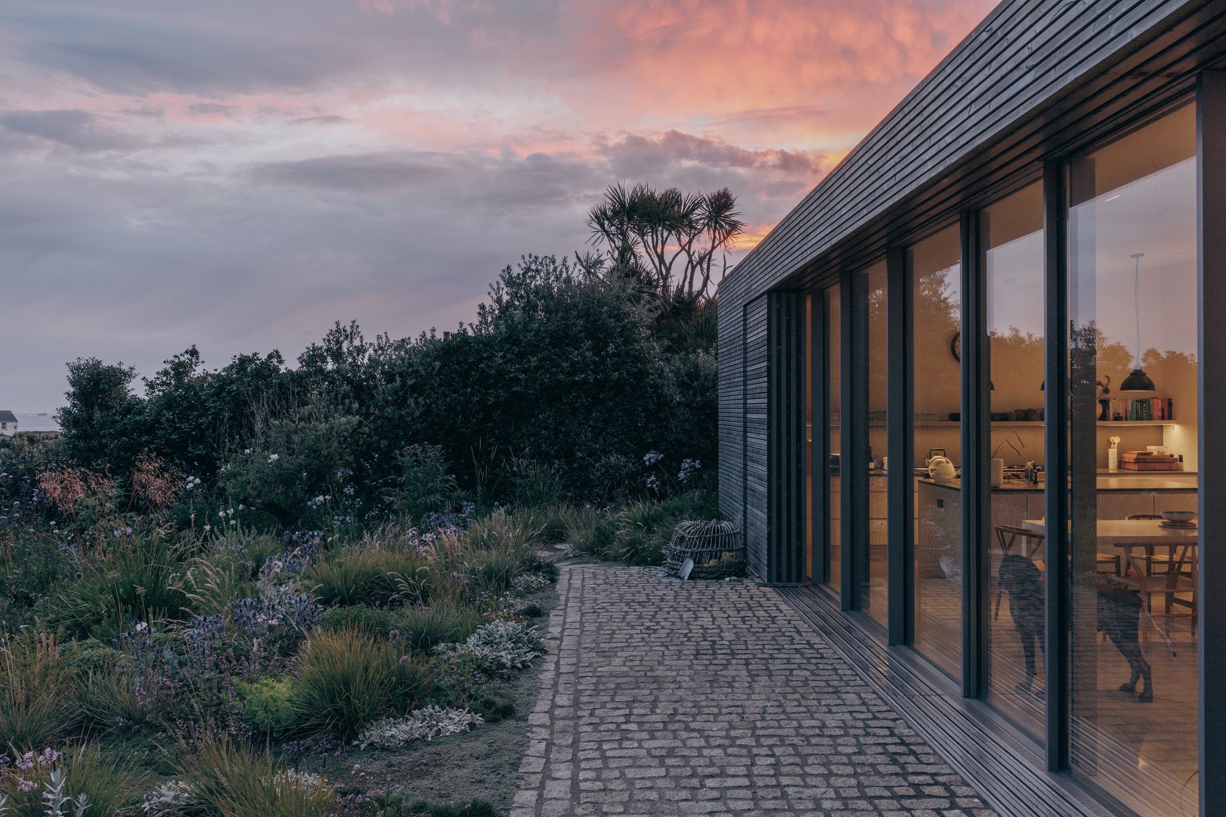 Garden terrace beside the glazed timber extension at dusk on Bryher