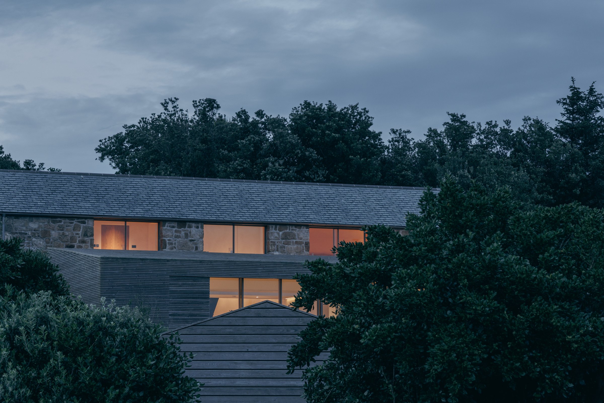 View from the garden back to the renovated granite cottage and timber extension at dusk
